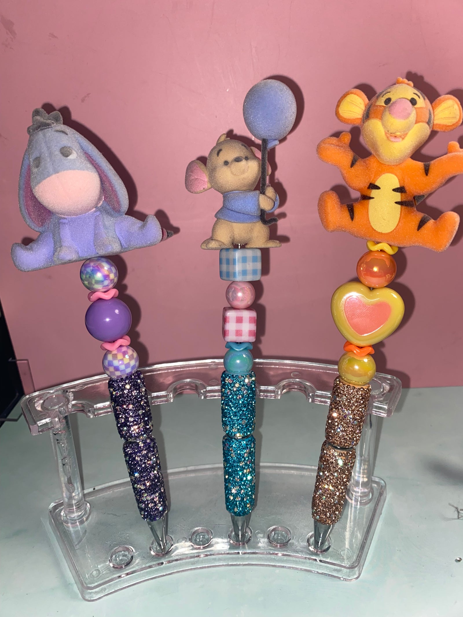 Three hand-beaded character pens on a display stand